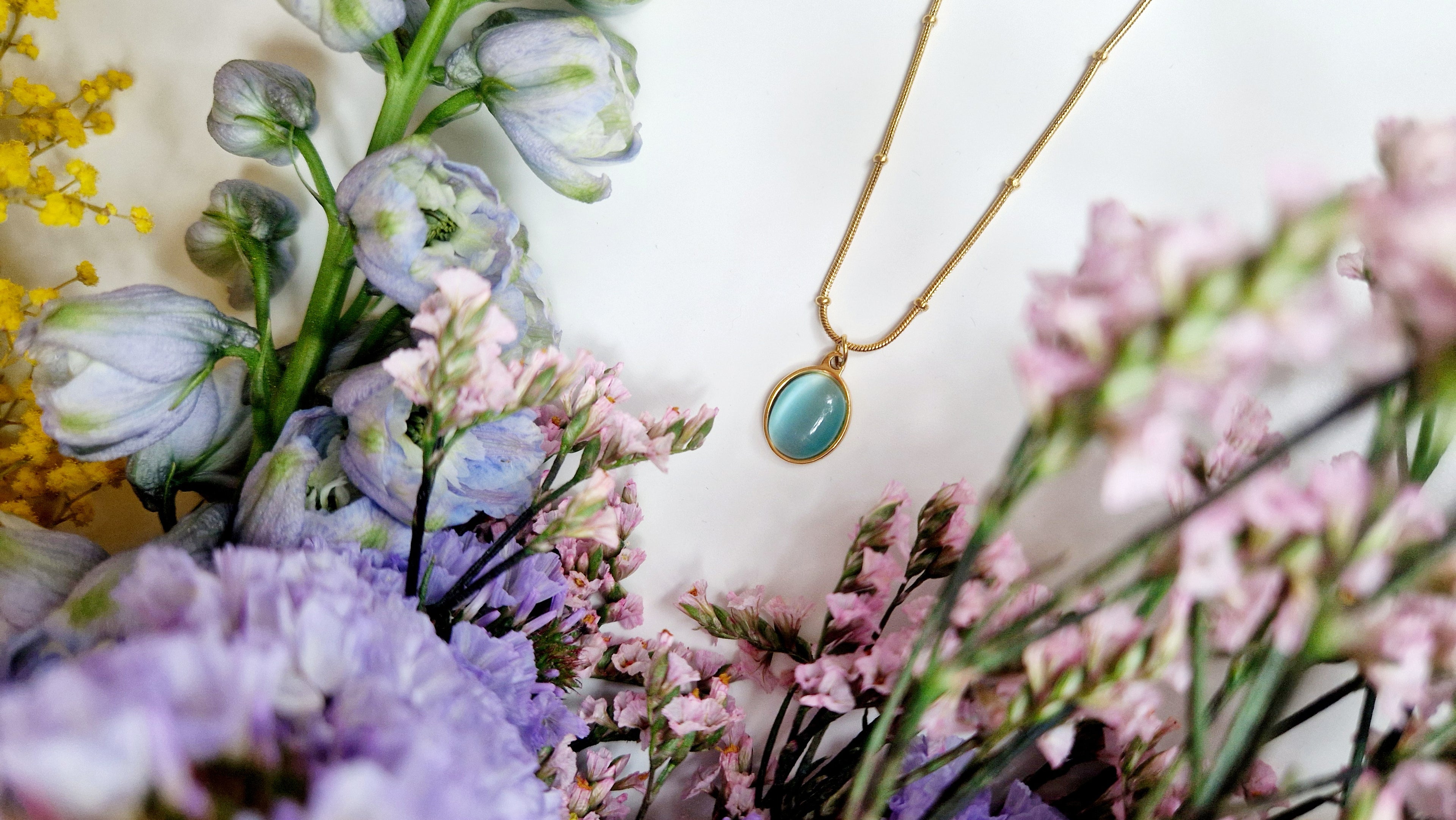 aquamarine gold pendant necklace surrounded by fresh flowers