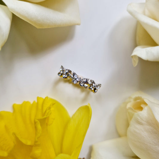 Silver butterfly ring surrounded by flowers. Top view