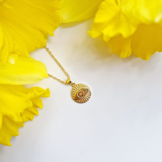 a gold chain necklace with a circular evil eye pendant